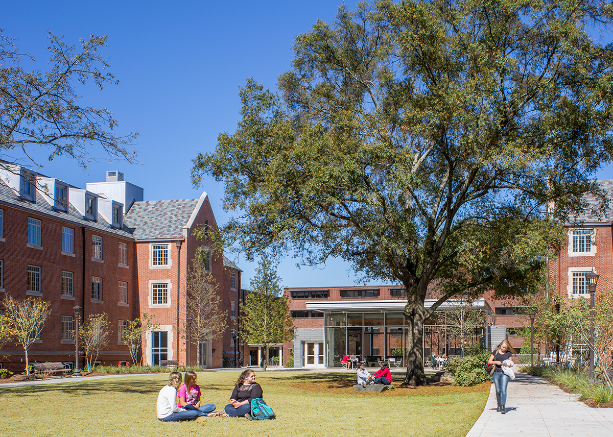 Students walking and sitting on the lawn of east campus near Glenn.