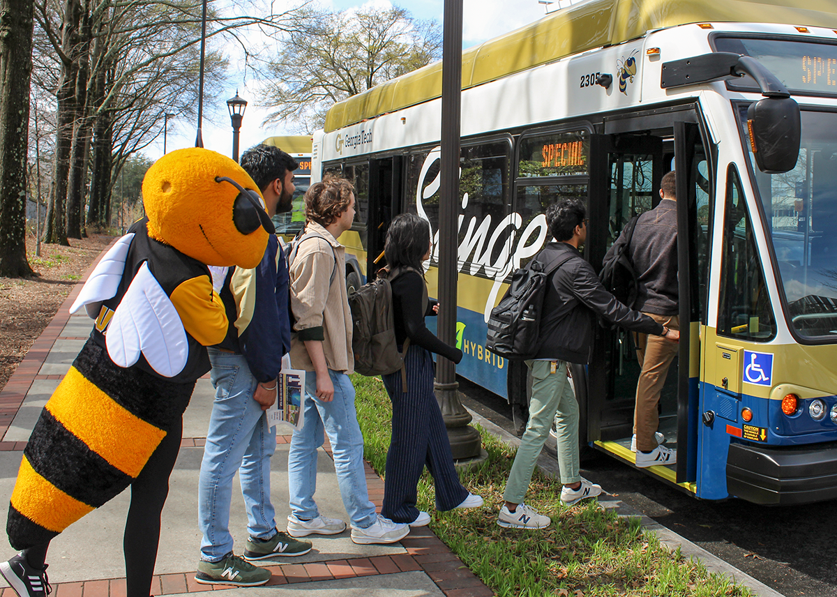 Buzz and a group of GT students getting on a hybrid Singer bus.