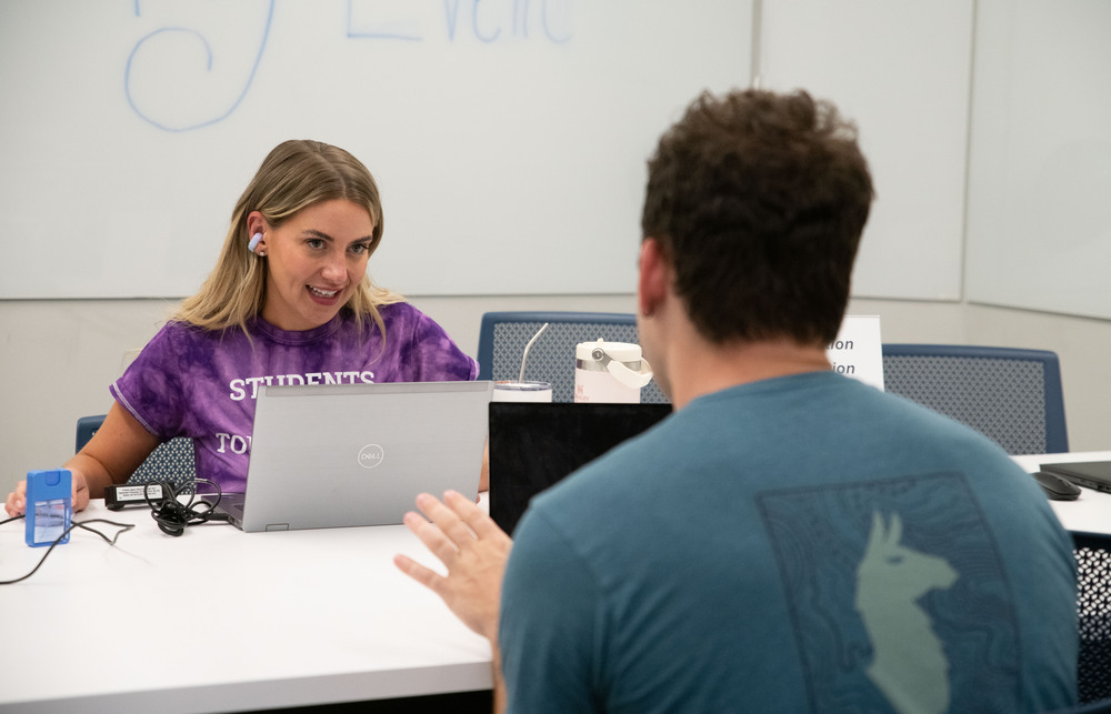 Staff member assisting a student while at a laptop